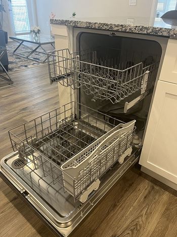 A dishwasher with its door open and racks inside.